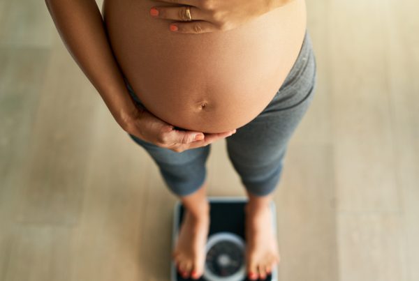 pregnancy by the pounds. cropped high angle shot of a pregnant woman weighing herself on a scale.