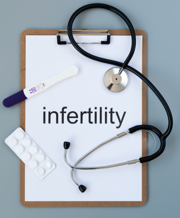 Prancheta com a palavra infertilidade, teste de gravidez, estetoscópio e cartela de comprimidos, representando investigação e plano de tratamento em fertilidade.