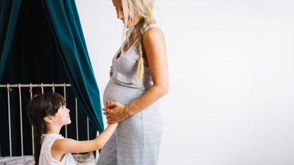 Mulher grávida em maternidade independente segurando a mão de uma criança, representando a reprodução solo e a construção de uma família monoparental.