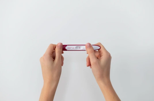 Mulher segurando um teste de gravidez enquanto enfrenta infertilidade inexplicada, mesmo com exames de fertilidade normais.